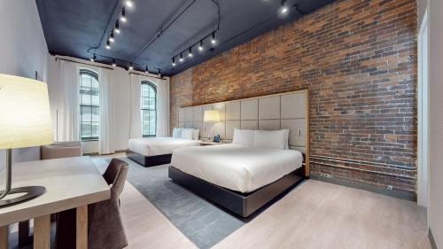 a bedroom with two beds and a brick wall at Studio 154 Luxury Hotel in Nashville