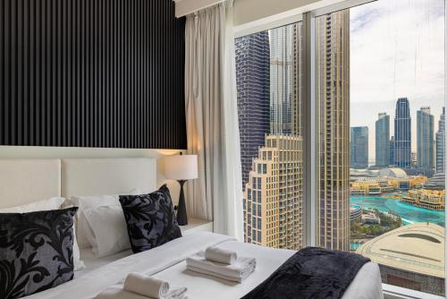 a hotel room with a bed and a large window at Luxury 4BR Burj Khalifa & Fountain Views in Dubai