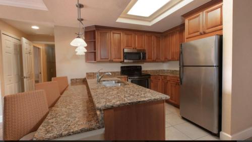 a kitchen with wooden cabinets and a stainless steel refrigerator at Westgate Town Center Resorts in Orlando