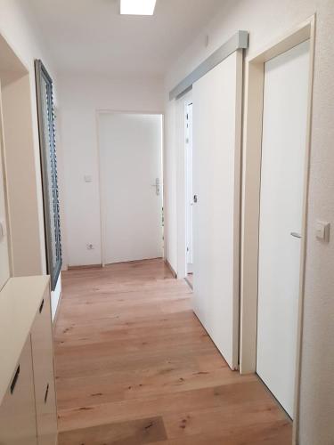an empty hallway with two doors and a wooden floor at Sonnige 3 Zimmer Ferienwohnung Sun Mountain in Rechberghausen