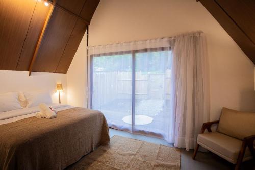 1 dormitorio con 1 cama y ventana con silla en Cabana Pitomba - Viagem Inspirada en Fernando de Noronha