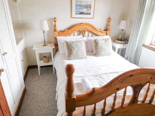 a bedroom with a wooden bed with white sheets and pillows at Bofin in Glentrasna