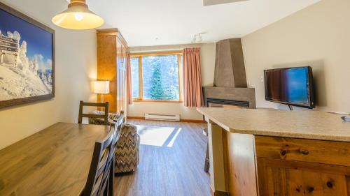ein Wohnzimmer mit einem Tisch und einem Flachbild-TV in der Unterkunft Cahilty #357 home in Sun Peaks