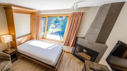 ein kleines Schlafzimmer mit einem Bett und einem Kamin in der Unterkunft Cahilty #357 home in Sun Peaks