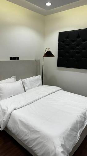 a bedroom with a white bed with a black headboard at Studio Al Aqiq in Riyadh