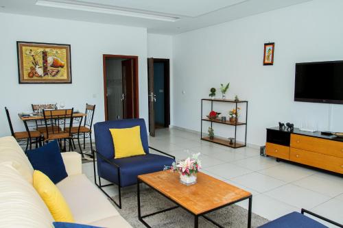 a living room with a couch and chairs and a tv at Residences Saint Pierre in Abidjan