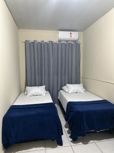 two beds in a room with gray curtains at Hotel Nossa Senhora de Lourdes in Trindade