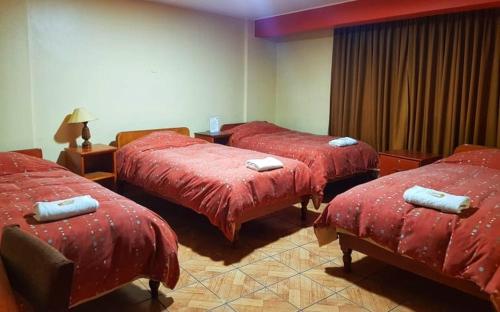 a room with three beds with red comforters at Hatun Wasi Huaraz in Huaraz