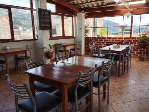 a restaurant with wooden tables and chairs and windows at Hatun Wasi Huaraz in Huaraz