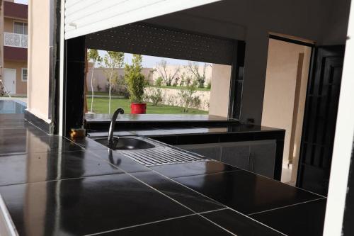 Luxurious & panoramic views في مراكش: مطبخ أسود مع حوض ونافذة