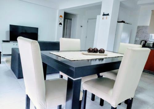 a dining room with a black table and white chairs at Dreams in Río Gallegos