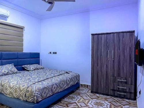 um quarto com uma cama azul e um armário de madeira em Adnan Lodge em Tamale