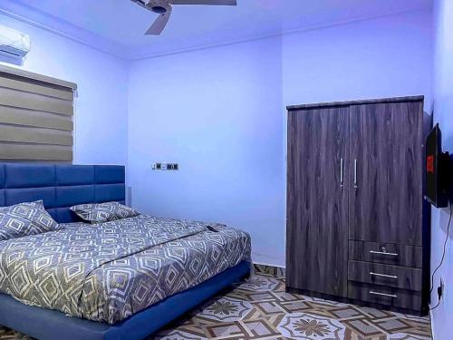 a bedroom with a blue bed and a wooden cabinet at Adnan lodge in Tamale