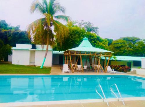 a swimming pool with a gazebo and a palm tree at Hotel Pallara Campestre in Ricaurte