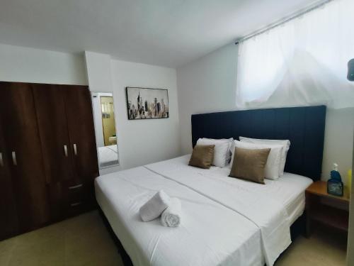 a bedroom with a large white bed with a blue headboard at Suite Hermosa ven descansa o trabaja El Rodadero Santa Marta in Gaira
