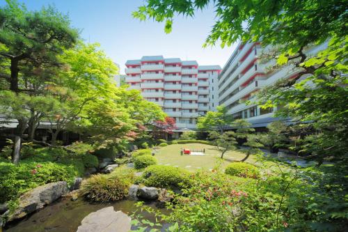Kinugawa Grand Hotel Yumenotoki في نيكو: اطلالة على حديقة بها نهر ومباني