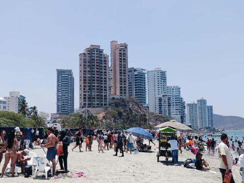 a group of people on a beach with tall buildings at Suite Hermosa ven descansa o trabaja El Rodadero 50m Playa in Gaira