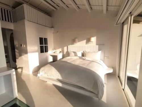 a bedroom with a white bed and a large window at Ample Villa 小希臘民宿 in Ruifang