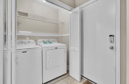 a white laundry room with a washer and dryer at 3C Mariners Walk by AvantStay Beach Pool Access Enclosed Porch in Isle of Palms