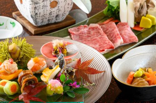 a table topped with plates of food and meats at Kinugawa Grand Hotel Yumenotoki in Nikko