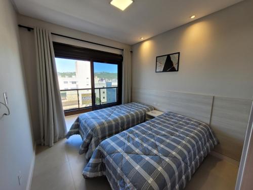 a hotel room with two beds and a window at Recanto Dos Girassois 408 in Bombinhas