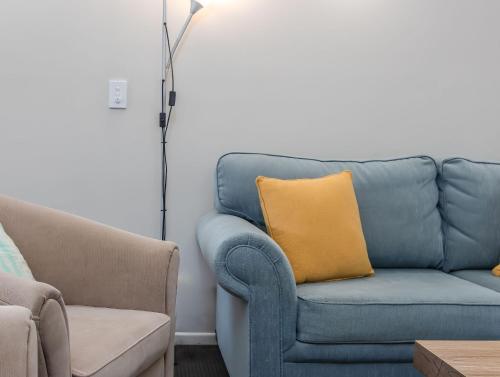 a blue couch with a yellow pillow in a living room at Hastings Cove Holiday Apartments in Hastings Point