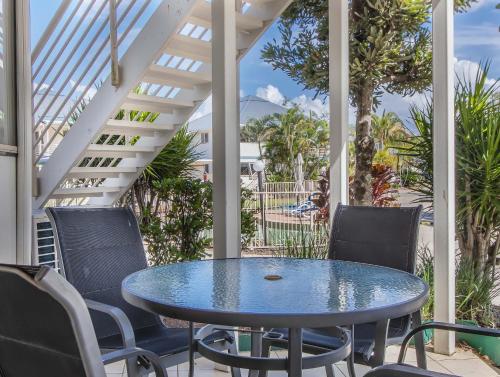 a patio with a blue table and chairs on a porch at Hastings Cove Holiday Apartments in Hastings Point