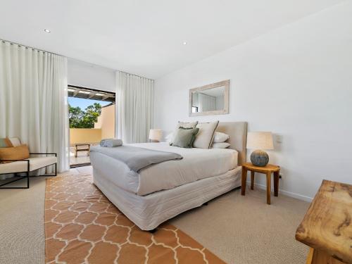 a white bedroom with a bed and a couch at Noosa Dreaming in Noosa Heads