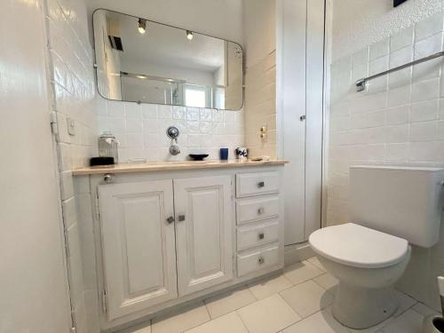 La salle de bains blanche est pourvue de toilettes et d'un miroir. dans l'établissement Sainte Maxime Sémaphore : Haut de Villa T4, Piscine, Terrasse, Clim, Proche Mer - FR-1-226-531, à Sainte-Maxime