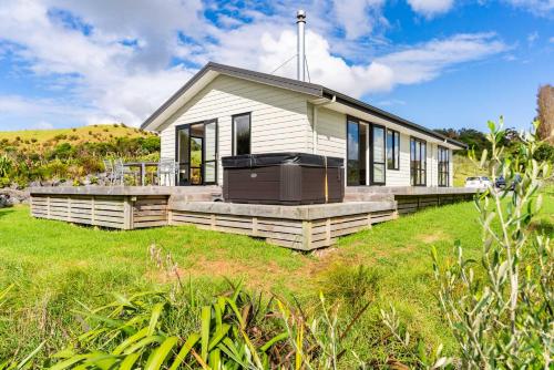a small white house on a grass field at The Olive Hut - Mangawhai Holiday Home in Wellsford