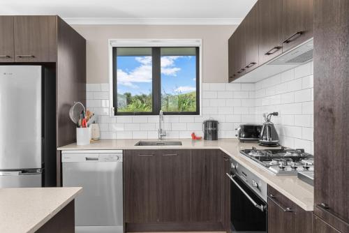 a kitchen with a sink and a stove top oven at The Olive Hut - Mangawhai Holiday Home in Wellsford