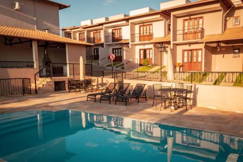 a pool with chairs and tables next to a building at Casa NR 2 Hospedaria in Tiradentes