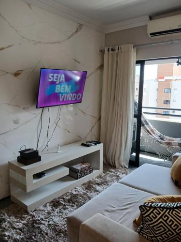 a living room with a tv on a wall at Flat Fortaleza Saint Martin in Fortaleza