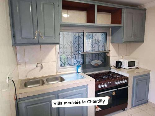 eine kleine Küche mit blauen Schränken und einer Mikrowelle in der Unterkunft Dany Chantilly in Jaunde