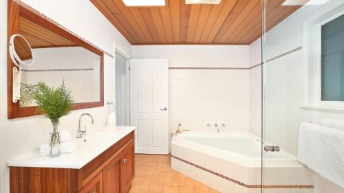 uma casa de banho com uma banheira, um lavatório e um espelho. em Southrose Cottage em Moss Vale