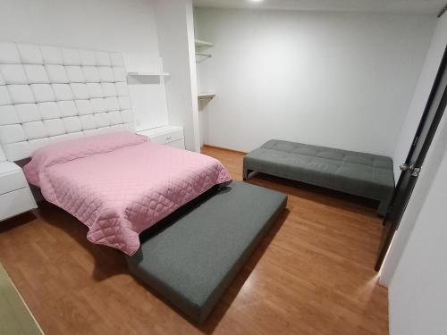Dormitorio pequeño con cama rosa y banco en Loft Santa rosa, en Apizaco
