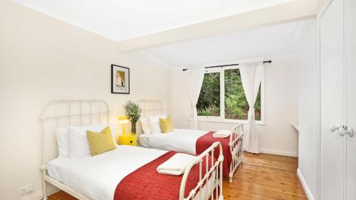 Duas camas num quarto branco com uma janela em Southrose Cottage em Moss Vale