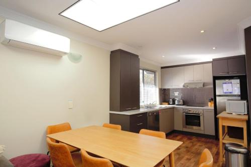 a kitchen with a wooden table and a dining room at Bogong Bungalow - 2, 19 Bogong Street in Jindabyne