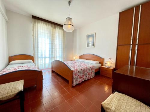 sypialnia z 2 łóżkami i stołem w obiekcie Luminous flat with terrace 250m from the sea w mieście Porto Santa Margherita di Caorle