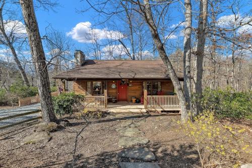 Cabaña de madera con puerta roja en el bosque en A Cozy 2BR Log Cabin Getaway-Mirror Lake-Fireplace cabin, en Lake Lure