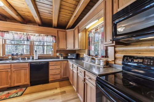 eine große Küche mit Holzschränken und schwarzen Geräten in der Unterkunft Vacation cabin in Lake Lure - Mirror Lake - great family space! W-Fi cabin in Lake Lure