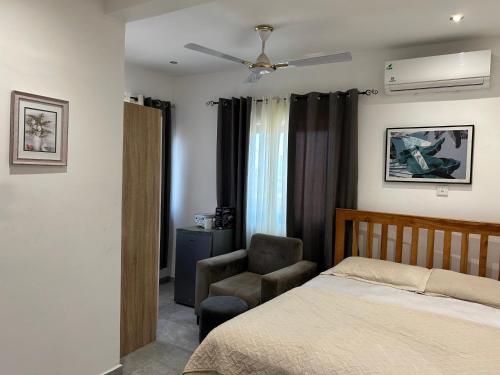 una camera da letto con un letto e una sedia di Dabs Apartments a Accra