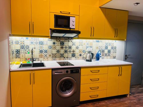 une cuisine avec des armoires jaunes et un lave-linge dans l'établissement Secrets Room Baku, à Baku