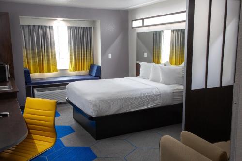 Microtel Inn & Suites by Wyndham Searcy في سيرسي: غرفه فندقيه بسرير وكرسي اصفر