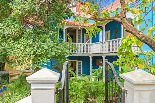 a blue house with a white porch at Curaçao Gardens in Willemstad