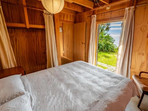 um quarto com uma cama e uma grande janela em The Gatehouse - Takaka Holiday Home em Takaka