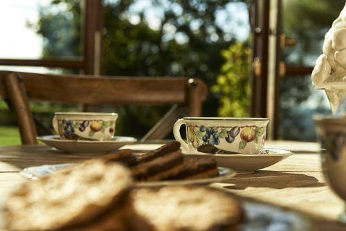 a wooden table with two cups and plates of bread at Villa Medicea di Lilliano in Grassina