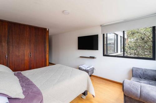 1 dormitorio con 1 cama, TV y silla en Enorme Casa Campestre en Bogotá, en Bogotá