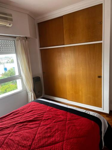 a bedroom with a red bed and a large wooden closet at Departamento En San Martin in San Martín