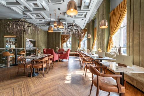 a restaurant with long tables and chairs and windows at The Sir Thomas Hotel in Liverpool
